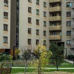 Contemporary high-rise apartment buildings with lush greenery and pathways in the courtyard.