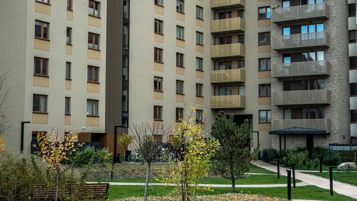 Contemporary high-rise apartment buildings with lush greenery and pathways in the courtyard.
