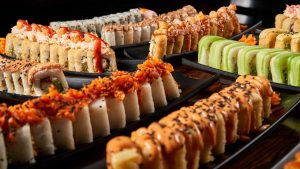 Close-up of colorful sushi rolls with diverse toppings on black plates, showcasing vibrant Japanese cuisine.