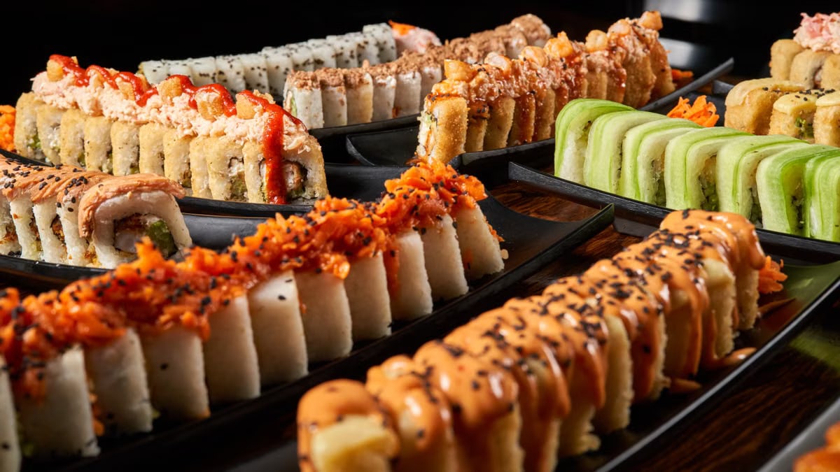 Close-up of colorful sushi rolls with diverse toppings on black plates, showcasing vibrant Japanese cuisine.